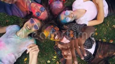 远离快乐的朋友，多种族的群体，在聚会后躺在草地上，五颜六色的脸和衣服在动