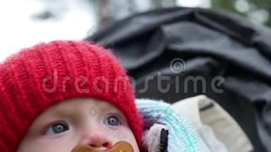 秋天，一个戴着红色针织帽子的孩子和一个坐在轮椅上的奶嘴