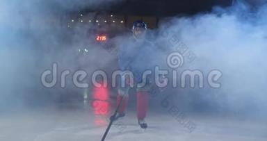 职业<strong>冰球运动</strong>员带着棍子和<strong>冰球</strong>在鲁达身上移动，穿着溜冰鞋和头盔在黑暗的背景和烟雾中移动