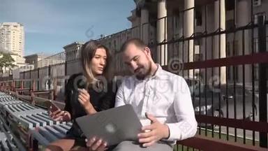 在阳光明媚的天气里，女生和同学<strong>用</strong>笔记本<strong>电脑</strong>在长凳上交流。 高清高清