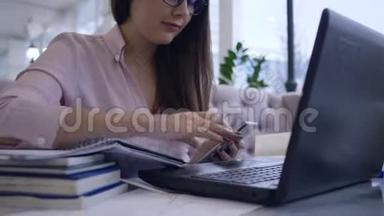 在线课程，女学生结合工作和学习使用现代笔记本电脑技术与<strong>手机</strong>和书籍<strong>制作</strong>