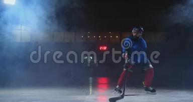 职业<strong>冰球运动</strong>员带着棍子和<strong>冰球</strong>在鲁达身上移动，穿着溜冰鞋和头盔在黑暗的背景和烟雾中移动