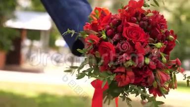 男人给女孩<strong>一束红玫瑰</strong>。 特写镜头。 新郎给他心爱的新娘送花。 新娘持有