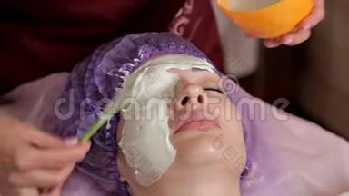 一位经验丰富的美容师为客户准备了一个健康的面具。 她站起来用刷子摸脸。 A.
