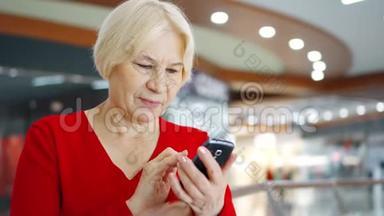 <strong>商场</strong>的高级妇女使用手机。 在购物<strong>中</strong>心浏览手机的女购物者