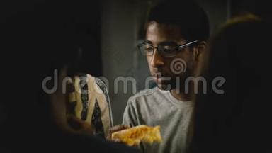 非裔美国年轻人在一个休闲的家庭聚会上吃披萨。 年轻人在家里的厨房里享受快餐。