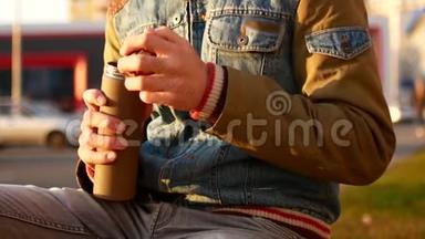 一个男人正在街上喝热水瓶里的茶。 秋，环境消费的概念.. 家庭咖啡