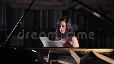女孩坐在钢琴旁学习音乐，音符。 音乐，表演，还有笔记