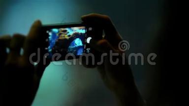 女手剪影手握手机拍摄玻璃管后面的鱼在水水族<strong>馆</strong>。 动物园和海洋<strong>馆</strong>
