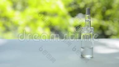 一个装有乳清的吸管的玻璃瓶放在一张白色的桌子上，背景是随风<strong>摇曳</strong>的<strong>树木</strong>