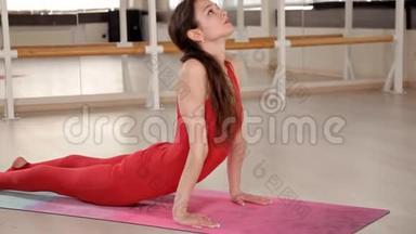 健康的年轻漂亮女孩穿着红色西装，<strong>坐在</strong>大厅<strong>地板上</strong>的地毯<strong>上</strong>做运动。 的概念