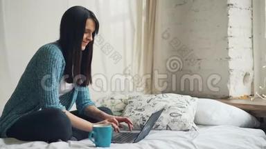 美丽的女人快乐的自由职业者在家工作，使用笔记本电脑，微笑着看屏幕，享受自由职业者