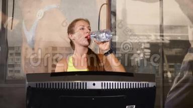 一幅年轻的运动女子行走轨迹的肖像。 可爱运动的女人在训练时喝水。 生活和运动