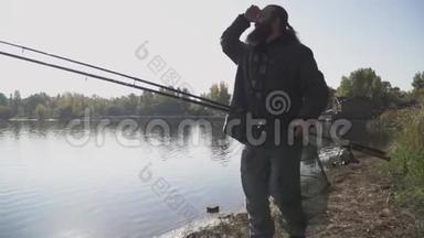 长胡子的孤独渔夫带着钓鱼竿在河岸上散步。 慢动作。