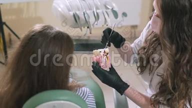 一名牙医对坐在椅子`她的病人解释说：“一名牙医对一名妇女进行了缓慢射击的特写镜头。