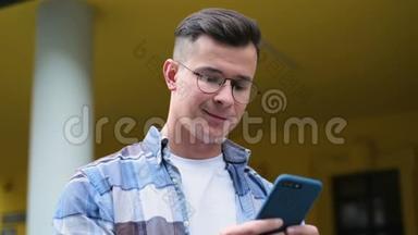 一位英俊的年轻人用智能手机在社交媒体上滚动，以设备、<strong>笑声</strong>和