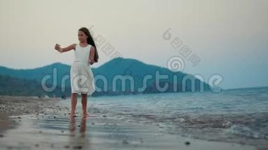 日落时分在海边的智能手机摄像头上摆姿势的小女孩