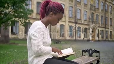 年轻的非洲女学生坐在长凳上，在大学附近的公园看书，准备<strong>上课</strong>