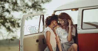 非洲和红头发的女孩，有着良好的心情，微笑和度过了一段美好的<strong>时光</strong>，坐在<strong>复古</strong>橙色的公共汽车前。