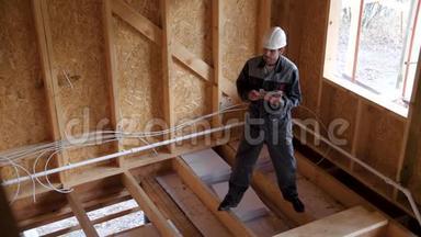 建筑师或建筑商检查半建木框架房屋的计划。 建筑工地上的微笑建筑工人