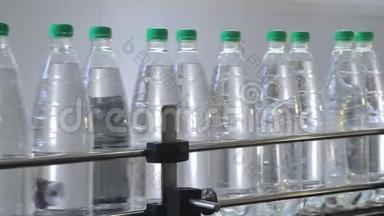 白色<strong>塑料</strong>瓶站在装瓶线上，装满<strong>矿泉水</strong>，用绿色的瓶盖堵塞