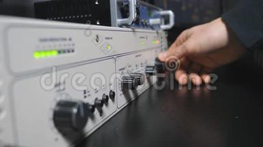 声音工程师的公手启动控制混音器面板上的<strong>音量</strong>旋钮。现代音频编辑器