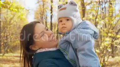 年轻的母亲和她的小儿子在秋天公园。 <strong>妈妈怀里</strong>的小男孩.. 4K