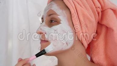 漂亮的年轻女人用刷子涂化妆品面膜。 健康和美丽的概念