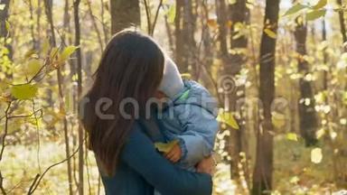 年轻的母亲和她的小儿子在秋天公园。 妈妈怀里的小男孩.. 4K