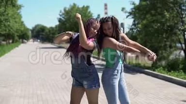 两个女孩的女朋友在阳光明媚的天气里在公园里快乐和愚弄。 慢动作