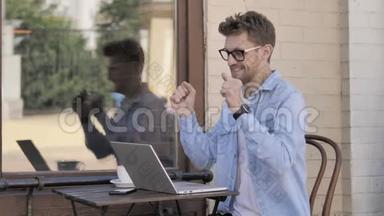 年轻人在笔记本电脑上庆祝成功，坐在户外
