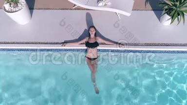 穿泳装的斯伦德女孩的无人机景在暑假的蓝色泳池边休息