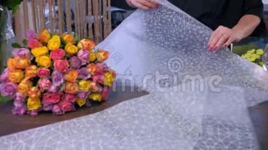 女花店正在花店用手工纸包装玫瑰花束。