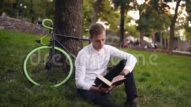 年轻严肃的白种人<strong>看书</strong>，坐在草地上城市公园，读书或<strong>看书</strong>，闲暇时间在