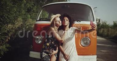 自拍时光在复古橙色巴士旁边，两个女孩金发和非洲卷发，穿着一个