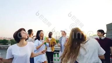 欢快的年轻男女在屋顶的户外聚会上慢动作，手里拿着装满苏打水和啤酒的瓶子。 主持人