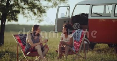 两个种族的朋友，一男一女，坐在大自然的中央野餐，令人惊叹的是喝酒和喝酒