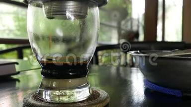 在咖啡厅用越南传统的phin过滤器酿造牛奶咖啡。 咖啡在杯子里慢慢滴下来