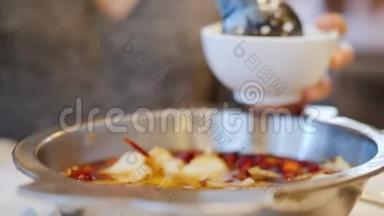女人把辛辣的海鲜汤倒在他的盘子里。 鱼片漂浮在加香料的肉汤里。 正宗中国菜