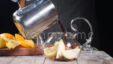 将热红葡萄酒倒入茶壶中，放入切片水果。 玻璃茶壶里放着橘子和柠檬，里面装满了热茶