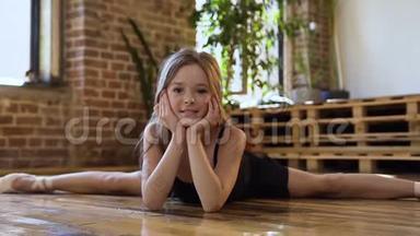 一个穿着黑色身体和裙子的美丽少年芭蕾舞演员在舞厅里做麻绳。 穿黑色紧身衣的舞蹈演员芭蕾舞演员