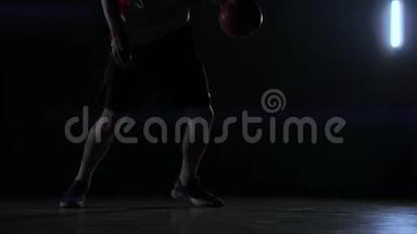 一个男子在黑暗的篮球场上打篮球，背景是烟雾中的篮球戒指