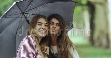 下雨天，两个微笑的<strong>女人</strong>在伞下直视着镜头。