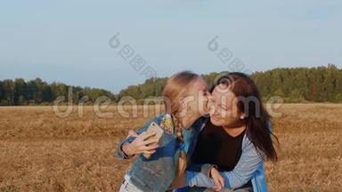 女儿亲吻妈妈，在<strong>夏季野外</strong>用手机拍照