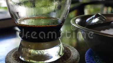 在咖啡厅用越南传统的phin过滤器酿造牛奶咖啡。 咖啡在杯子里慢慢滴下来