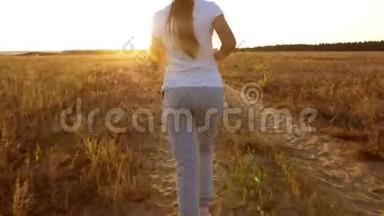 一个小女孩正在日落时分训练和听音乐，一个戴着耳机的运动女孩正在从事慢跑。后视图