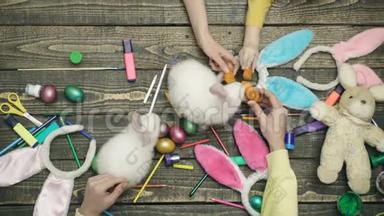 复活节兔子和复活节彩蛋的俯视图。有趣的复活节兔子在一张木桌上。准备复活节的快乐家庭。母亲