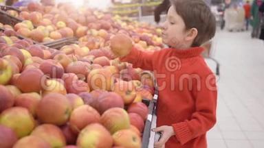 有趣的小男孩在超市的家庭购物中从盒子里摘苹果