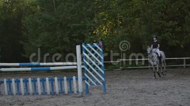 下面的动作，结束，低潮：骑马的女孩骑着强壮的棕色马，在阳光明媚的户外沙滩跑酷跳过篱笆