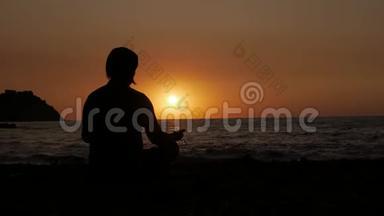日出时坐在海边沉思的人的剪影。